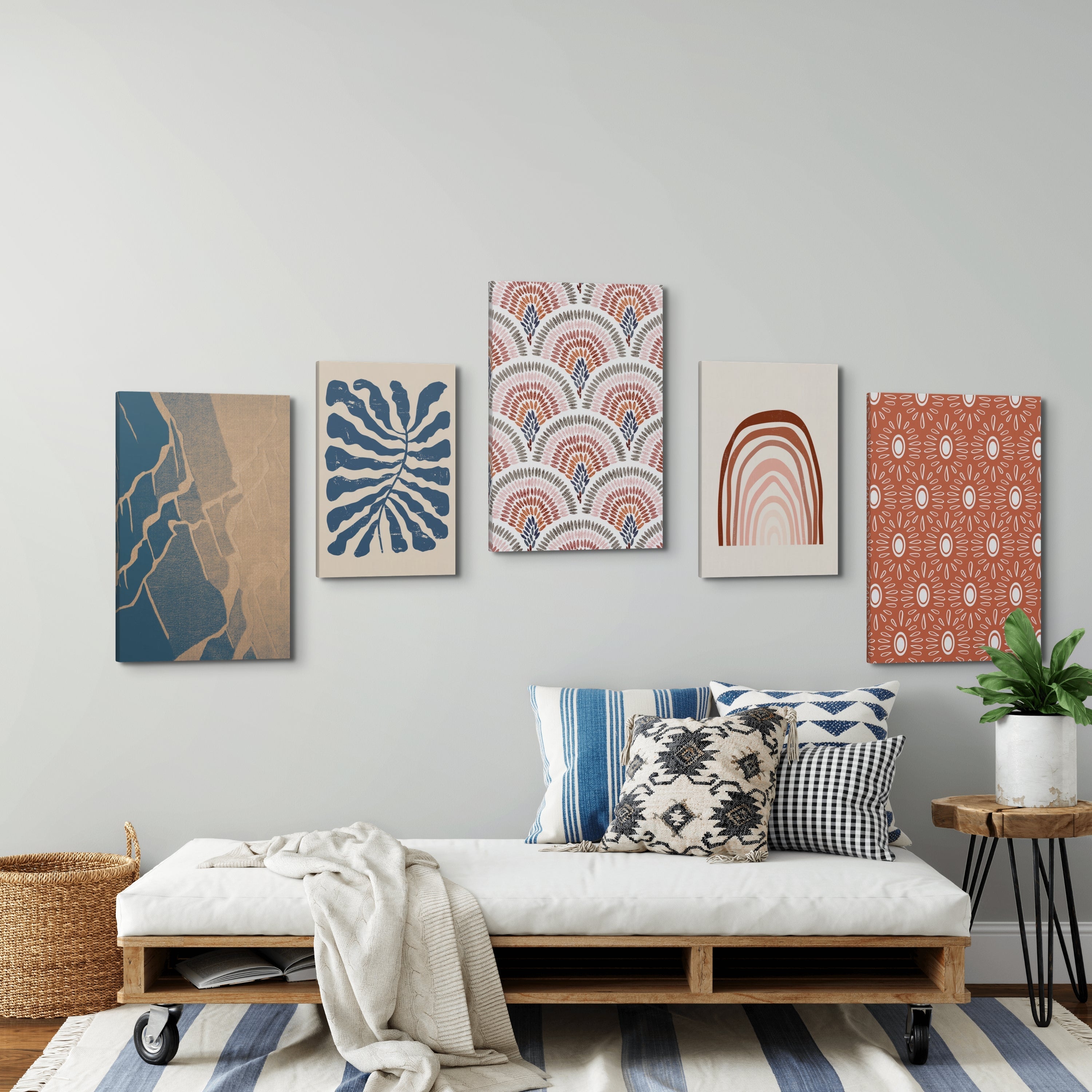 Gallery wall of easy to hang canvas prints hung above a couch in a living room area. The gallery wall has canvas of many different sizes, all vertical and are in a abstract, coastal theme with blue and orange as the color scheme. 