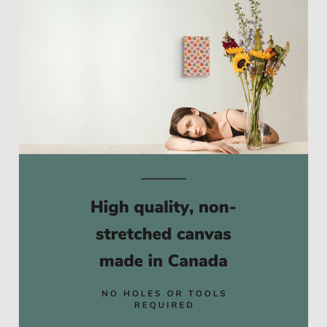 Lifestyle image of the vertical, 12x18 inch easy to hang canvas wall art hung in in a minimalist kitchen above a counter where a girl with a vase of flowers is sitting with graphic saying "High quality, non-stretched canvas made in Canada"