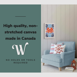 Lifestyle image of the vertical, 16x24” inch easy to hang canvas wall art hung in a coastal themed living room above a couch with graphic saying "High quality, non-stretched canvas made in Canada.