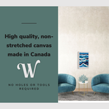 Lifestyle image of the vertical, 16x24” inch easy to hang canvas wall art hung in a coastal blue living room in-between two chairs with graphic saying "High quality, non-stretched canvas made in Canada"