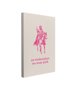 Single, 2:3 vertical easy to hang canvas print on a transparent background featuring an image of a minimalist pink cowboy riding a horse with his pistol drawn with vintage western font saying "on wednesdays we wear pink" underneath him on a beige background. 