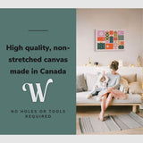 Lifestyle image of the vertical, 20x30 inch easy to hang canvas wall art hung in a living room above a couch with a mother and little girl opening gifts on christmas morning with graphic saying "High quality, non-stretched canvas made in Canada"