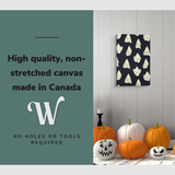 Lifestyle image of the vertical, 20x30” inch easy to hang canvas wall art hung in a Halloween decorated foyer above some pumpkins with graphic saying "High quality, non-stretched canvas made in Canada"