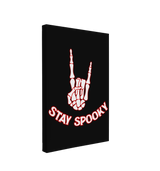 Single, 2:3 vertical easy to hang canvas print on a transparent background featuring an image of a white skeleton hand making the "Rock on" gesture, with a red outline on a black background with words "Stay Spooky" under it in a similar format. 