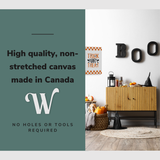 Lifestyle image of the vertical 16x24” inch easy to hang canvas wall art hung in a Halloween decorated hallway above a credenza with graphic saying "High quality, non-stretched canvas made in Canada."