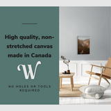 Lifestyle image of the vertical 16x24” inch easy to hang canvas wall art hung in a living room above an accent chair with graphic saying "High quality, non-stretched canvas made in Canada."